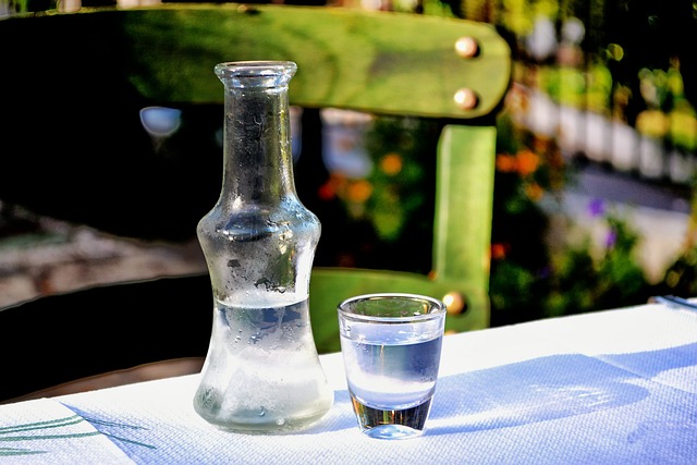 Une petite bouteille et un verre contenant de l'ouzo, apéritif anisé grec, sur une table