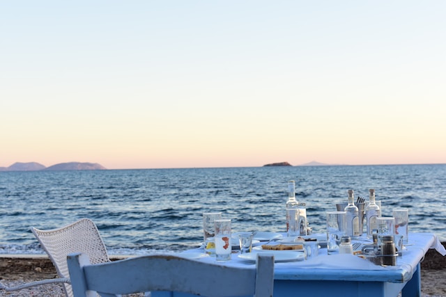 Une grande table au bord de la mer, avec ouzo et mezzedes, apéritifs grecs